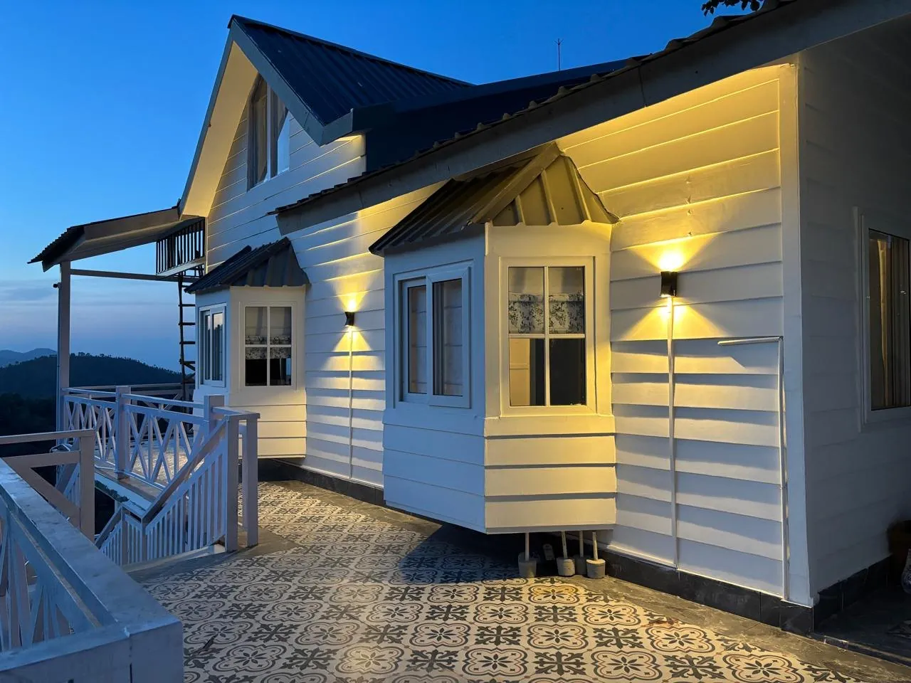 Namah Stay Himalayas cottage at blue hour with bay windows glowing under warm lamps
