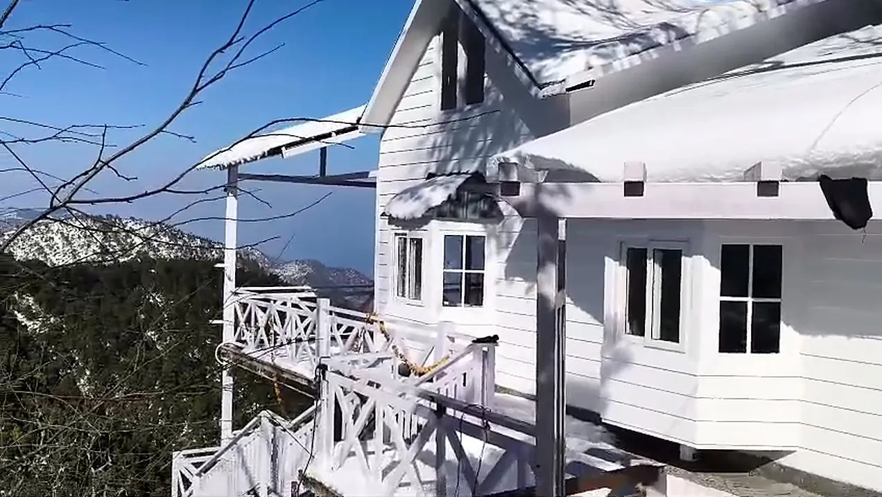 The cottage gable and railings under fresh snow on a clear winter morning