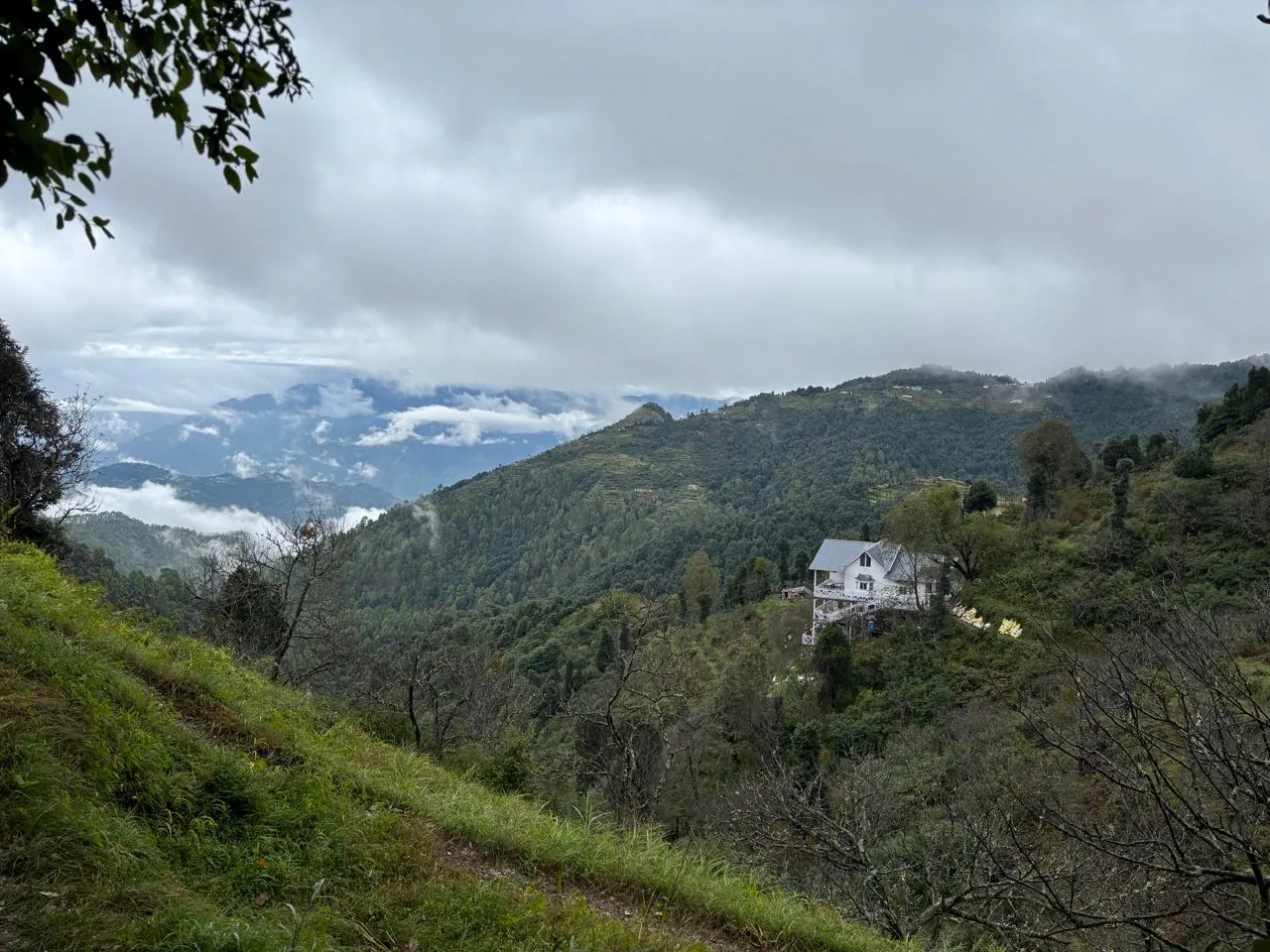 The cottage in a green monsoon valley with clouds rolling over the ridges