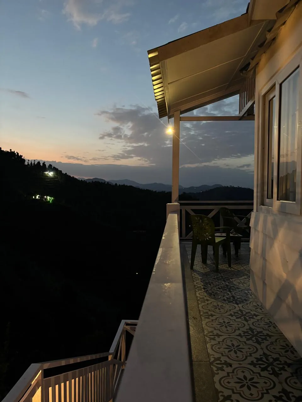 The verandah at blue hour, lamps lit, valley falling away below
