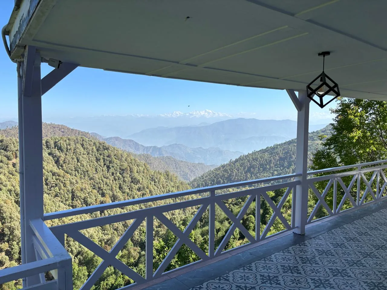 The covered verandah with white cross-braced railings looking over the Kanatal valley