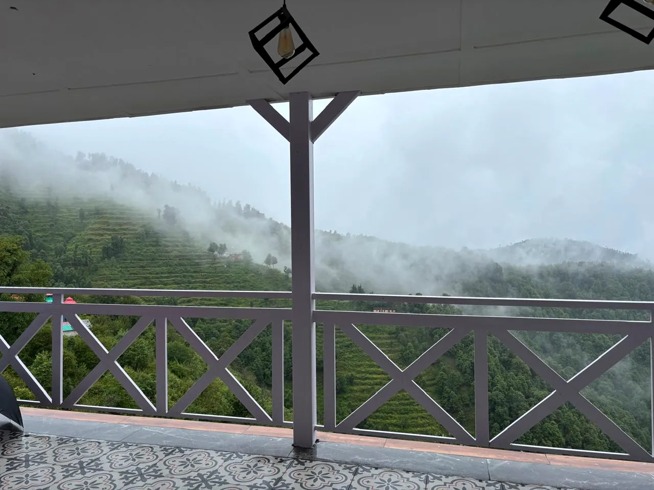 Monsoon mist drifting past the verandah railings at the homestay